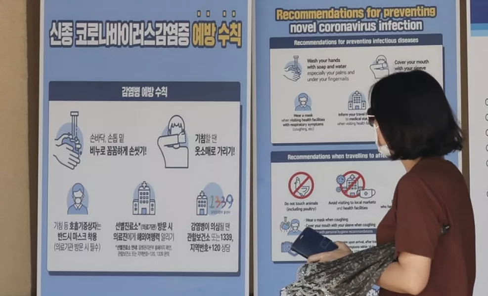 A visitor wearing a face mask walks near a banner showing precautions against coronavirus at the Gyeongbok Palace in Seoul (Lee Jin-man/AP)
