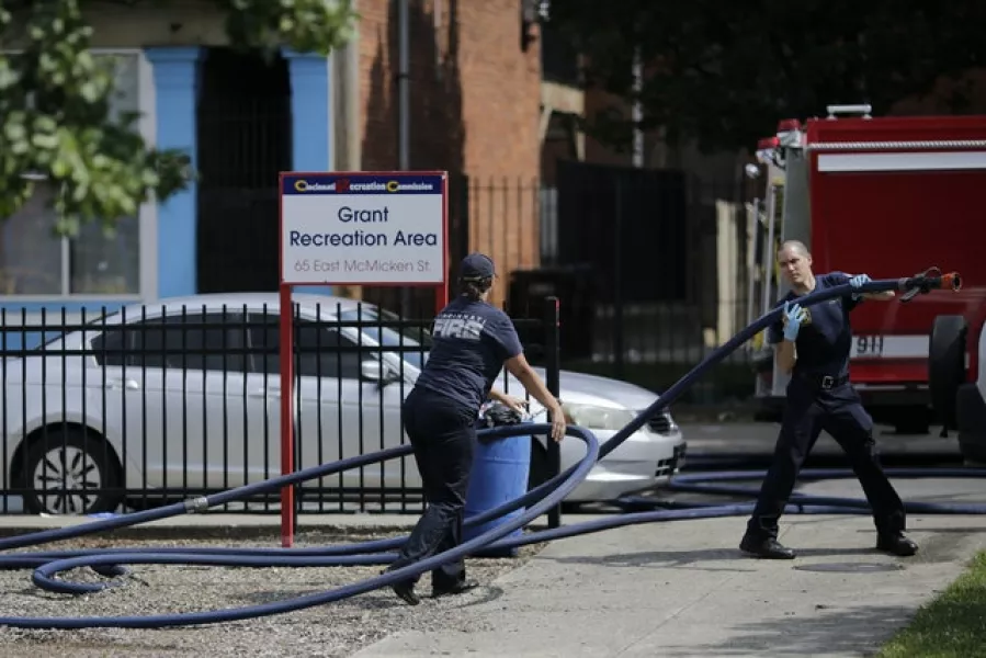 Cincinnati firefighters use bleach and a hose to clean and remove pools of blood left at the scene of a mass shooting near Grant Park in the Over-the-Rhine neighbourhood  (Sam Greene/The Cincinnati Enquirer/AP)