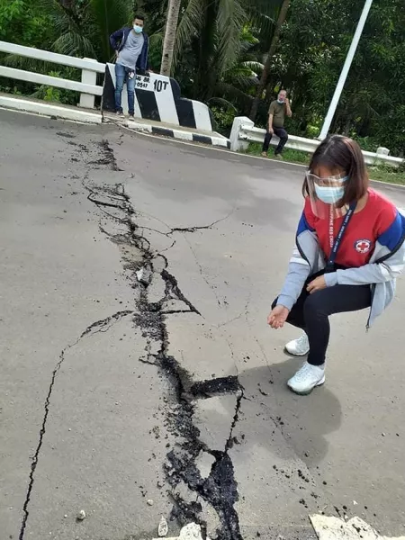 A volunteer looks at the cracks on a road after a quake struck in Cataingan, Masbate province, central Philippines (John Mark Lalaguna/Philippines Red Cross/PA)