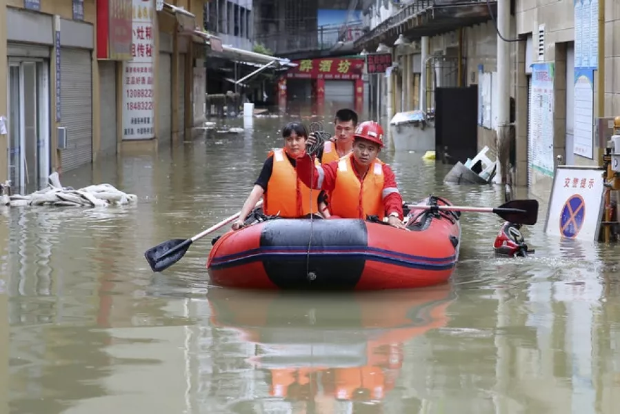 Rescuers use an inflatable boat as they evacuate people from a flooded neighbourhood in Neijiang in south-western China’s Sichuan Province (Chinatopix via AP)