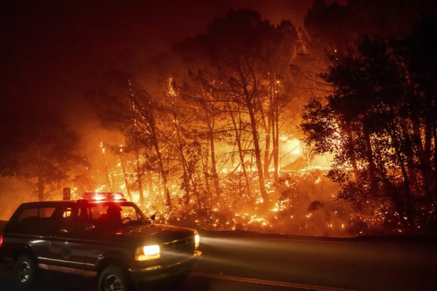 A fire vehicle passes burning trees near Winters (Noah Berger/AP)