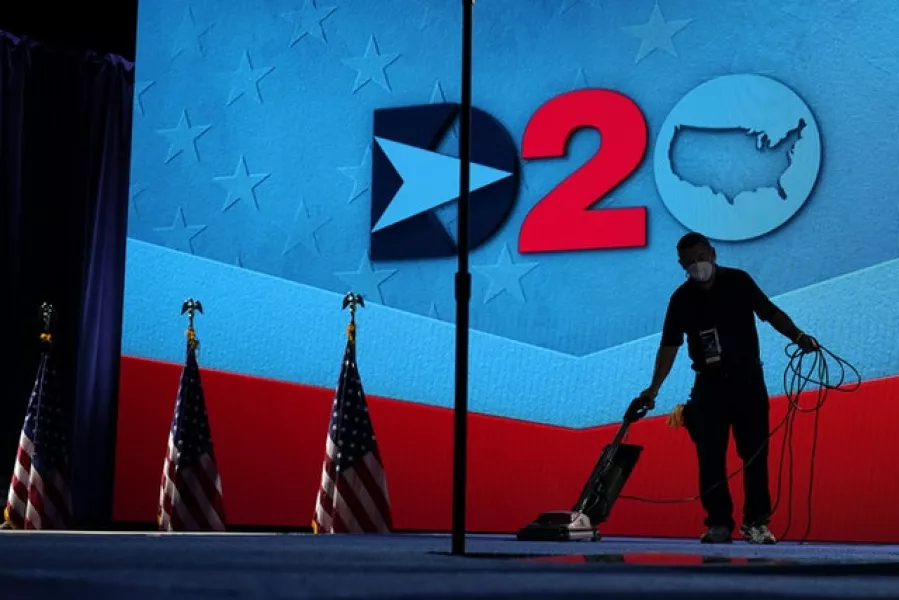 A worker vacuums the stage where Democratic vice presidential candidate Senator Kamala Harris will speak (Carolyn Kaster/AP)