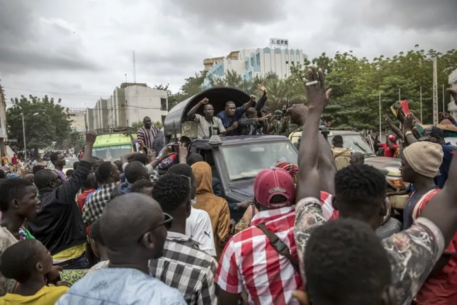 People cheer as security forces and others drive through the streets of the capital Bamako (AP)