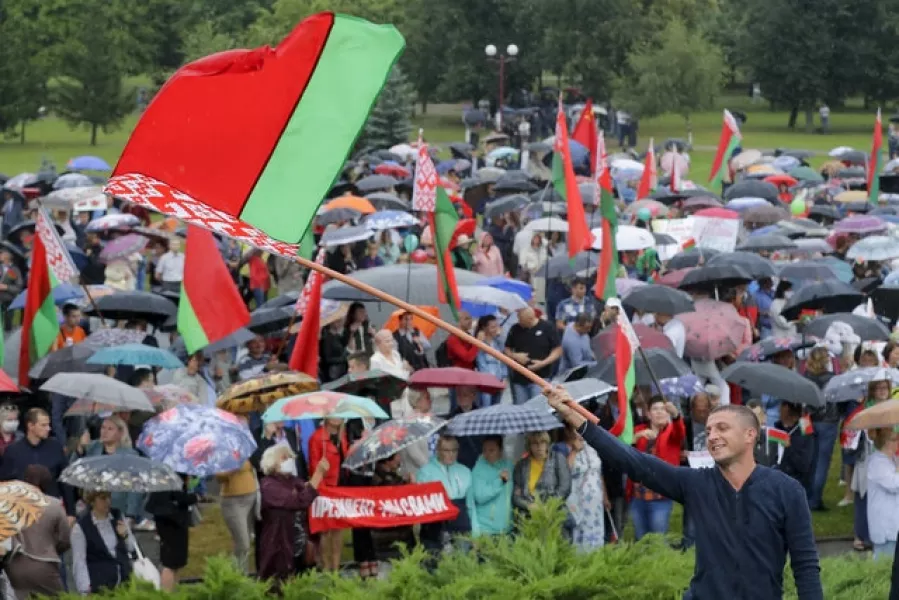 A man waves a Belarusian state flag as supporters of Alexander Lukashenko gather in a square in Minsk (Sergei Grits/AP)