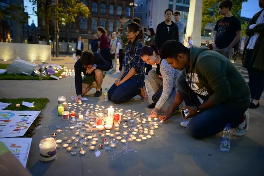People leave tributes and light candles by City Hall in Manchester for victims of the Manchester Arena bomb attack (Ben Birchall/PA)