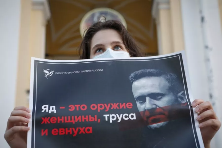 A protester holds a poster reading ‘poison is the weapon of a woman, a coward and a eunuch’ during a picket in St Petersburg (Elena Ignatyeva/AP)