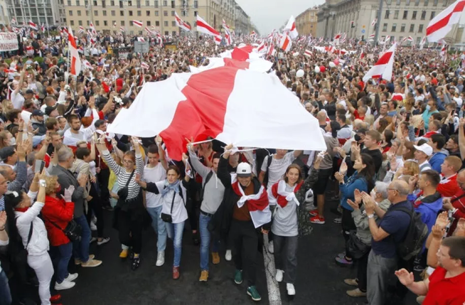 Demonstrators carry a huge historical flag of Belarus (Dmitri Lovetsky/AP)