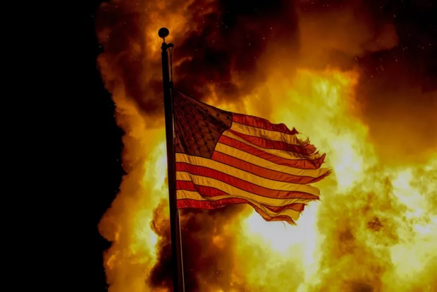 A flag flies over a department of corrections building ablaze during protests sparked by the shooting of Jacob Blake (Morry Gash/AP)