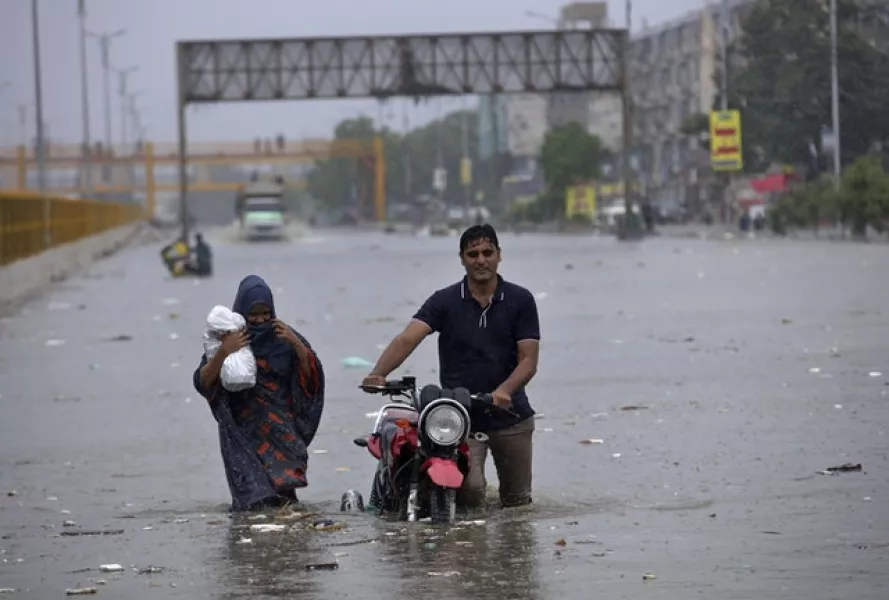 A family wades through a flooded road (AP/Fareed Khan)
