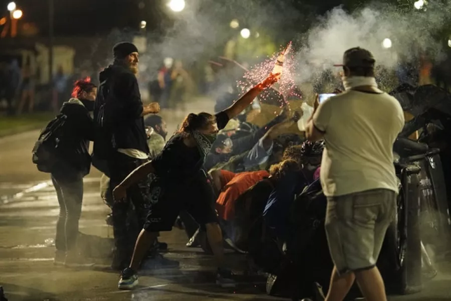 A protester throws an object towards police (AP/David Goldman)