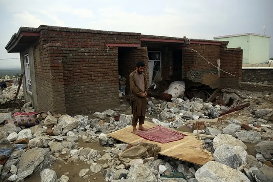 An Afghan man prays near his damaged house (AP/Rahmat Gul)