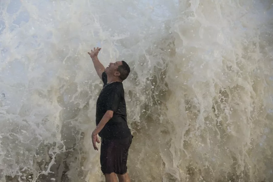 Water falls over a man as a wave hits the seawall while he watches the surf stirred up by Hurricane Laura in Galveston, Texas (Brett Coomer/Houston Chronicle via AP)