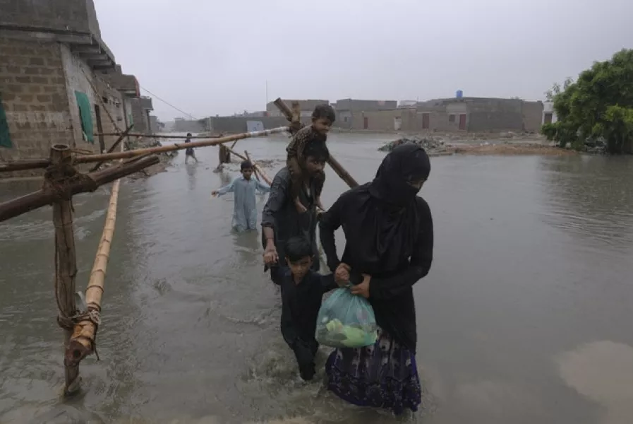 A family wades through a flooded area (Fareed Khan/AP)