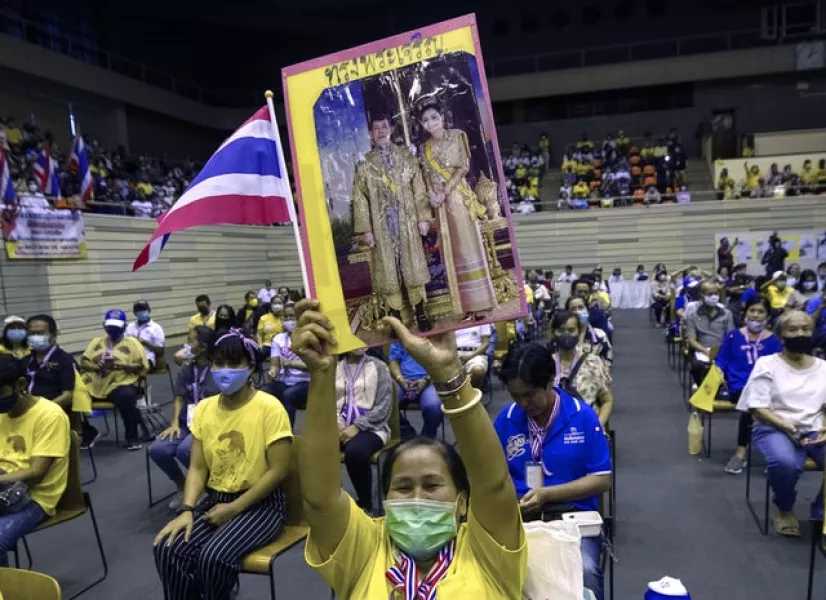 Supporters of the Thai monarchy hold up images of King Maha Vajiralongkorn and Queen Suthida during the rally (Sakchai Lalit/AP)