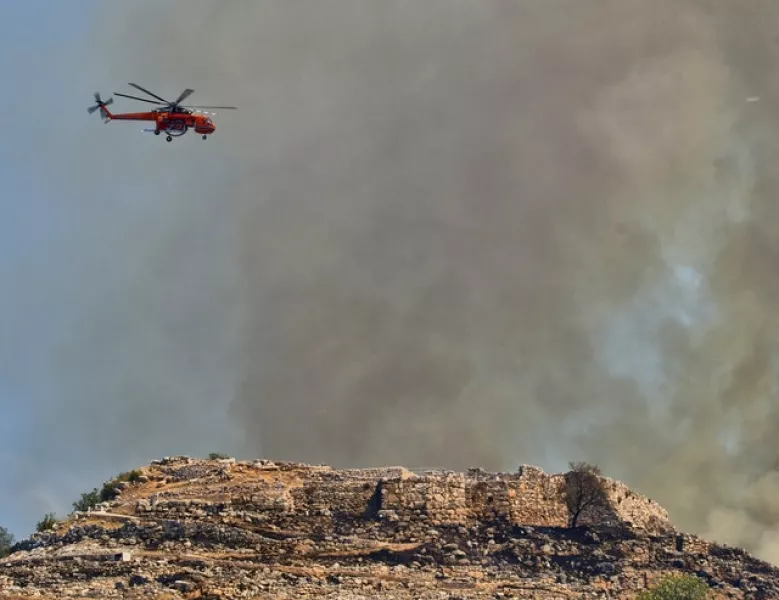 A helicopter operates during a wildfire over the ancient site of Mycenae (Vangelis Bougiotis/InTime News via AP)