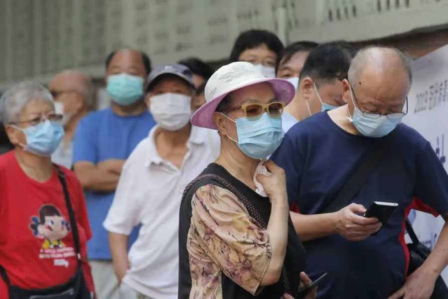 People wearing face masks queue for the coronavirus test (AP)