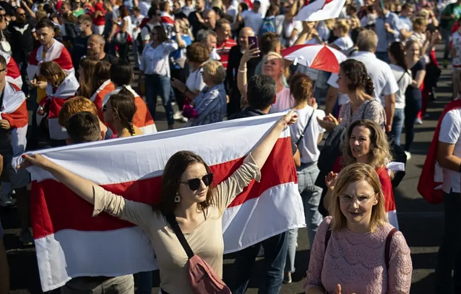 A Belarusian opposition supporter holds an old Belarusian national flag during a rally in Minsk (AP)