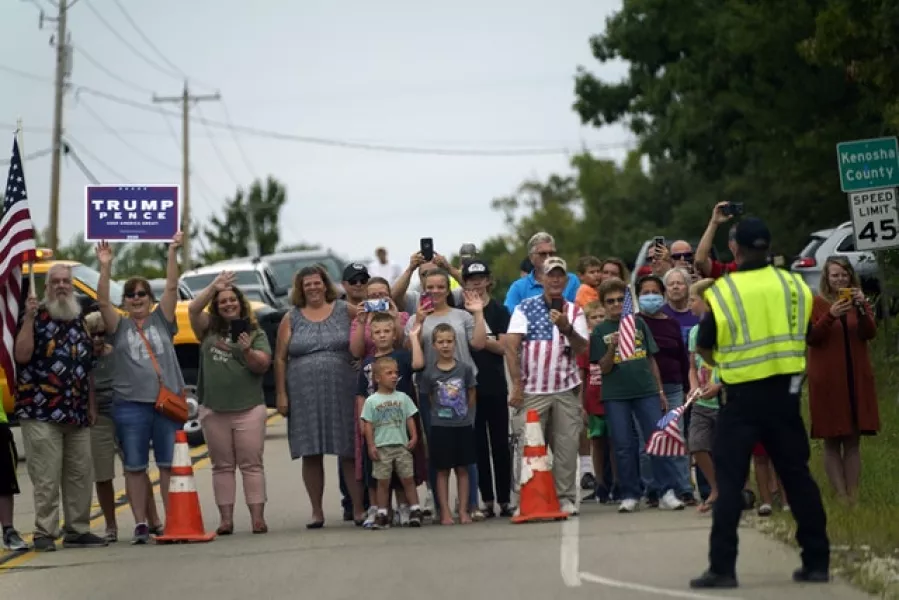 People line up to watch as the motorcade with President Donald Trump passes by (Evan Vucci/AP)