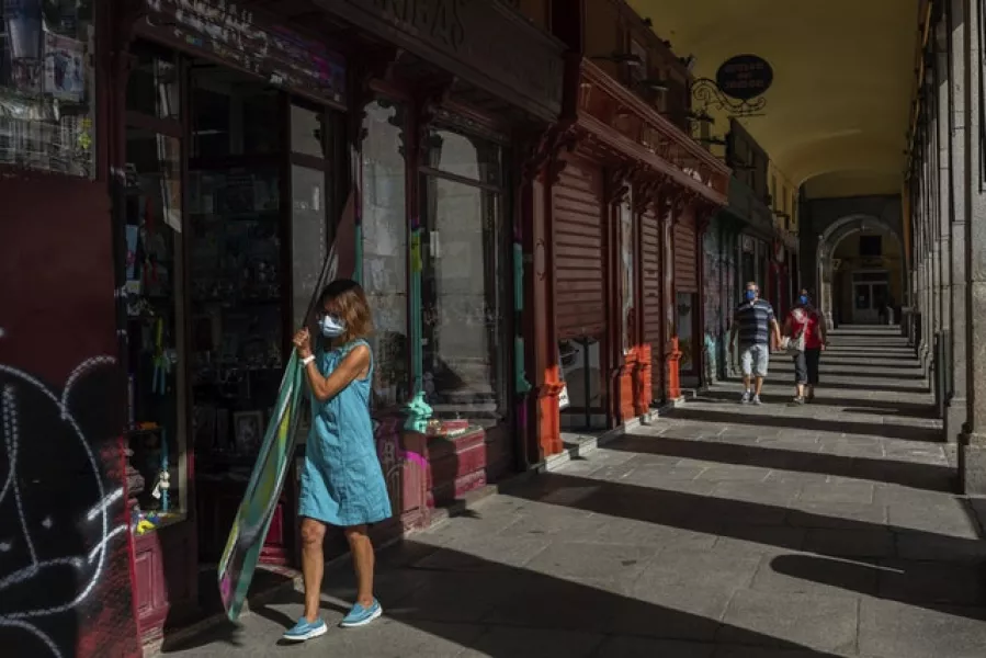 A woman opens a shop in Plaza Mayor in Madrid, Spain (Bernat Armangue/AP)