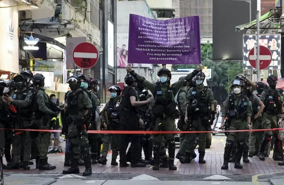 Hong Kong police officers raise a warning banner (Vincent Yu/AP)