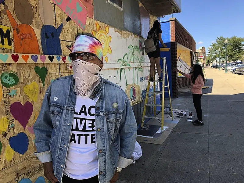 David Sanchez, a long-time Kenosha resident, watches volunteers paint murals on boarded-up businesses (Russell Contreras/AP)