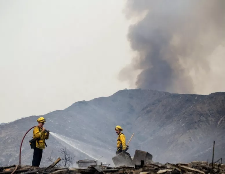 Firefighters extinguish hot spots at a structure destroyed by the El Dorado wildfire (Cindy Yamanaka/The Orange County Register/SCNG via AP)