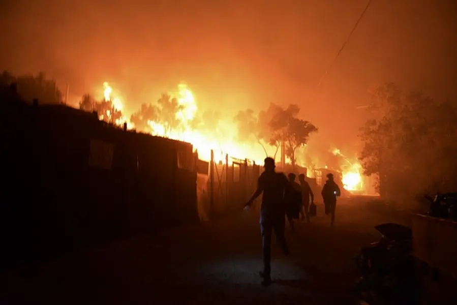 Refugees run as fire burns in the Moria refugee camp (Panagiotis Balaskas/AP)