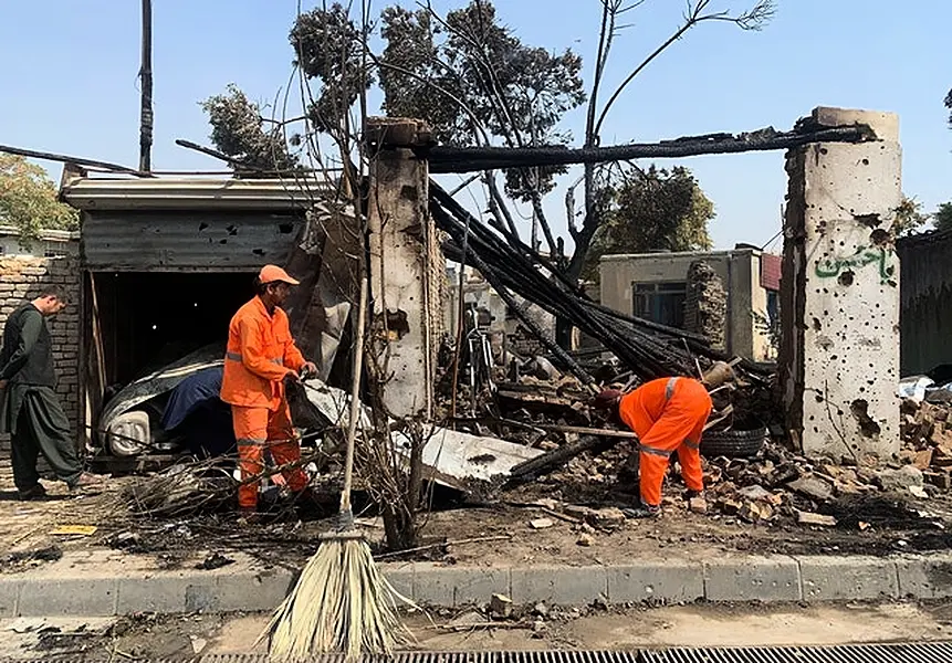 Municipality workers clear up after the blast (Rahmat Gul/AP)