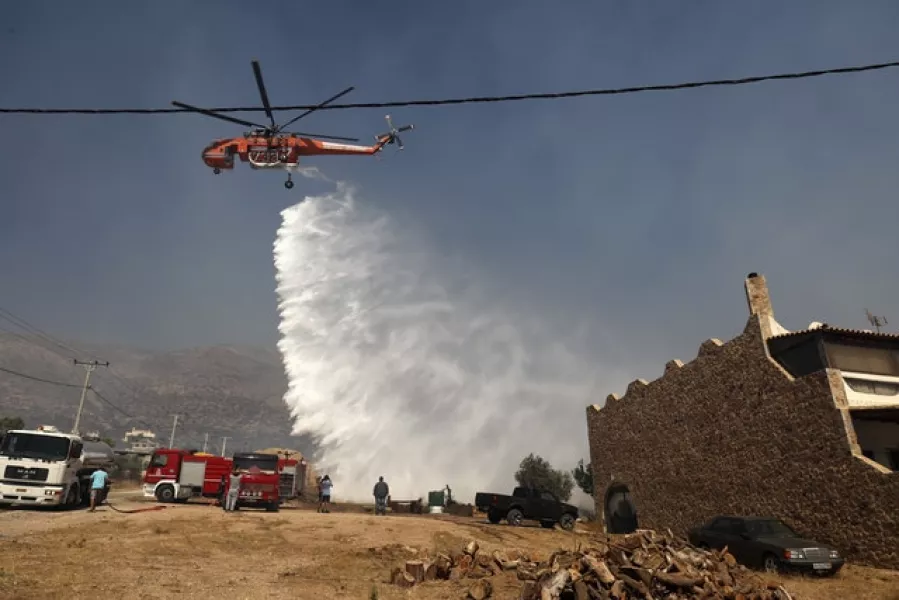 A helicopter drops water in a bid to tackle the raging fires (AP/Yorgos Karahalis)