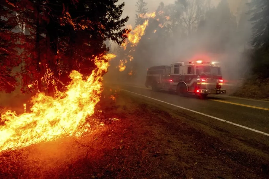 A fire engine drives past a fire on a highway near Fresno, California (Noah Berger/AP)