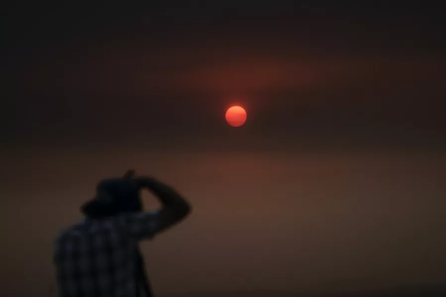 A man takes pictures of the sun through thick smoke in San Dimas, California (Jae C Hong/AP)