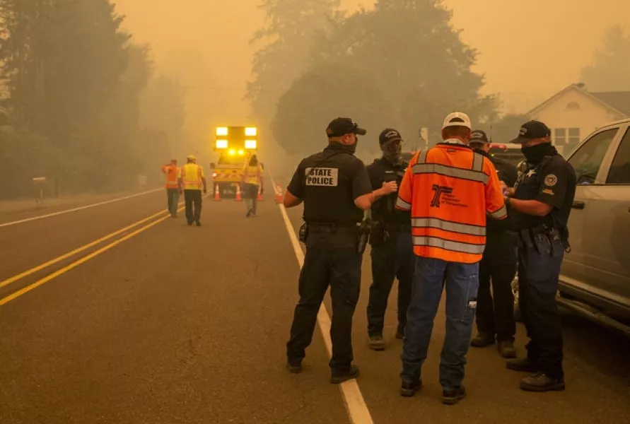 Police and other officials in Oregon confer at a roadblock (Andy Nelson/The Register-Guard via AP)