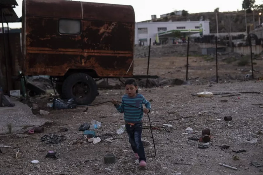 A migrant boy plays next to an abandoned vehicle (AP)