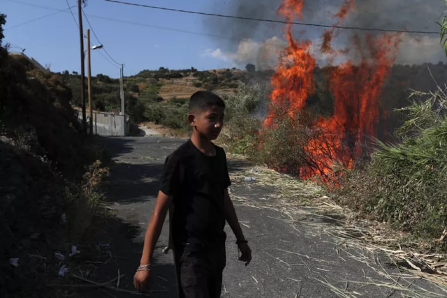 A migrant walks near a small fire in a field near Mytilene town (AP)