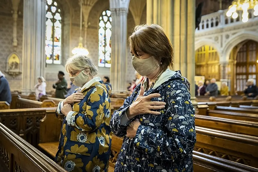 Parishioners wearing face masks bless themselves at the end of mass at St Patrick’s Catholic Cathedral in Armagh (Liam McBurney/PA)