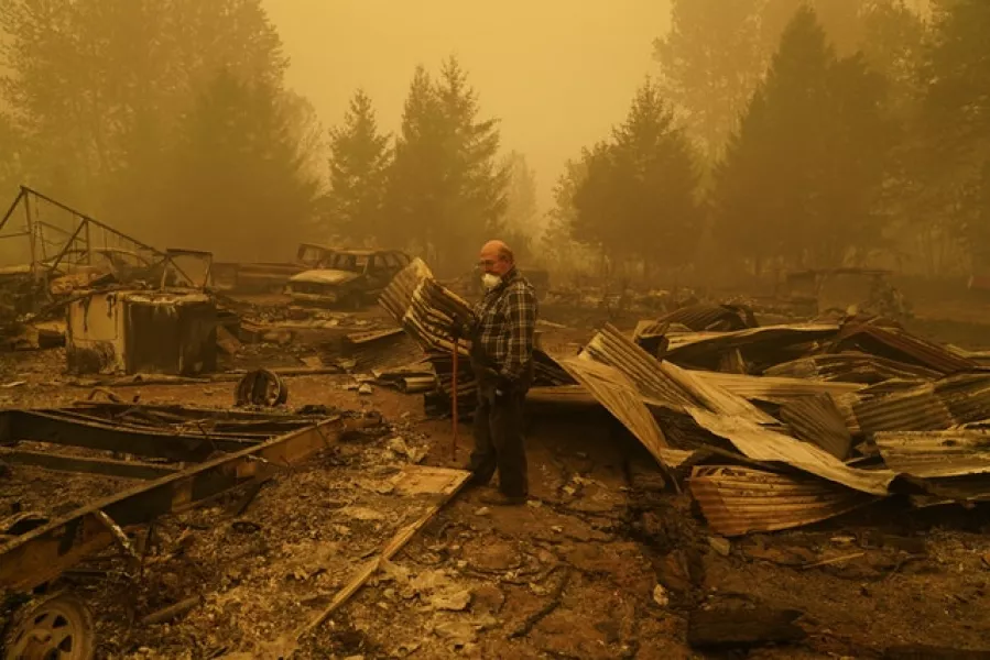 George Coble walks through what remains of a home on his property in Oregon (John Locher/AP)