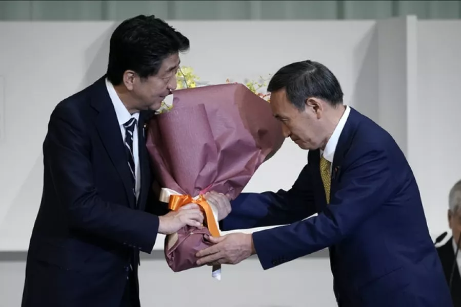 Shinzo Abe, presents his successor Mr Suga with flowers (AP)