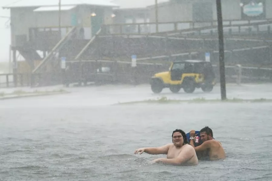 People play in a flooded car park in Pensacola Beach, Florida (Gerald Herbert/AP)