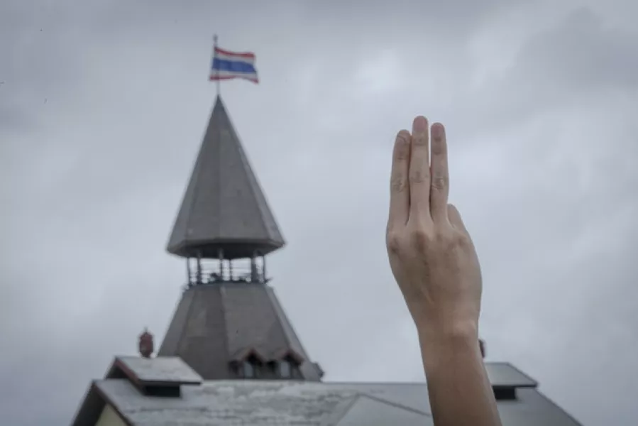 A pro-democracy demonstrator raises three fingers as symbol of resistance during a protest at the Sanam Luang park in Bangkok (AP)