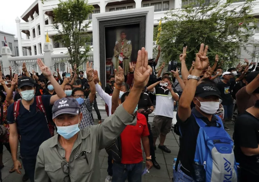Pro-democracy protesters hold up three fingers, the movement’s symbol of resistance salute, as they march close to Sanam Luang field in Bangkok (AP)