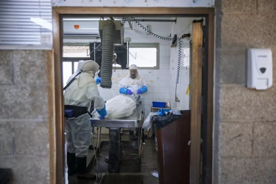 Workers from Israel’s official Jewish burial society disinfect a body at a special morgue for Covid-19 victims in Holon near Tel Aviv (Oded Balilty/AP)