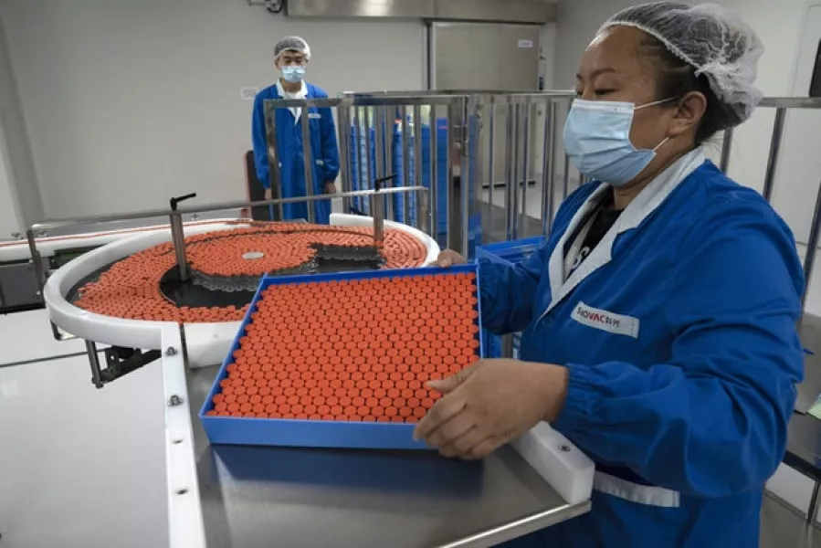 A worker feeds vials for production of the SinoVac vaccine (AP)