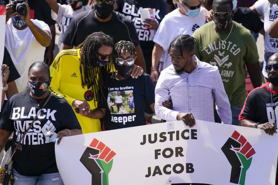 Jacob Blake’s sister Letetra Widman, centre, and uncle Justin Blake, left, march at a rally for Mr Blake in Kenosha in August (Morry Gash/AP)