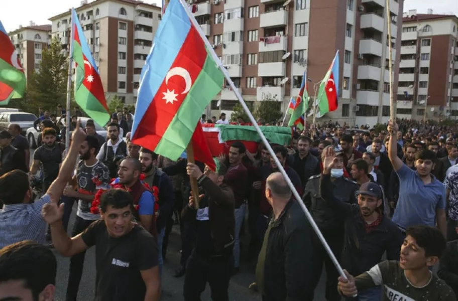People wave Azerbaijan national flags during a funeral ceremony of a member of the Azerbaijani Armed Forces who was allegedly killed during fighting over the region of Nagorno-Karabakh in Tartar (AP/Aziz Karimov)