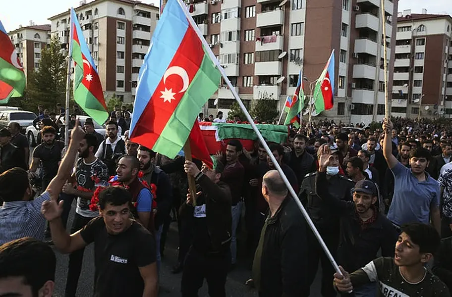 People wave Azerbaijan national flags during a funeral ceremony of a member of the Azerbaijani Armed Forces who was allegedly killed during fighting over the region of Nagorno-Karabakh in Tartar (AP/Aziz Karimov)