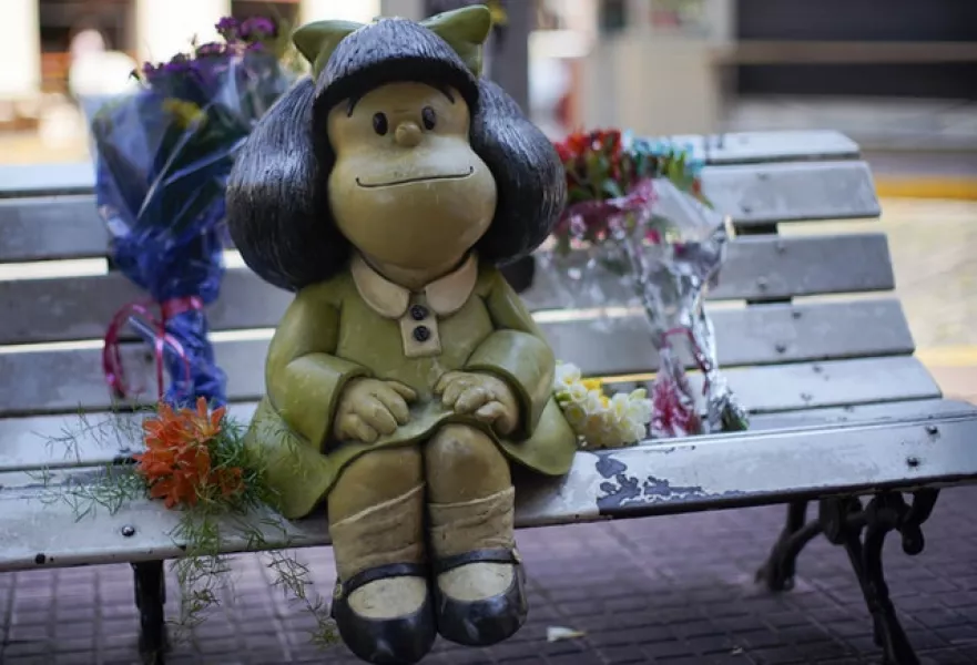 Flower bouquets flank a statue of the comic strip character Mafalda (Victor R Caivano/AP)