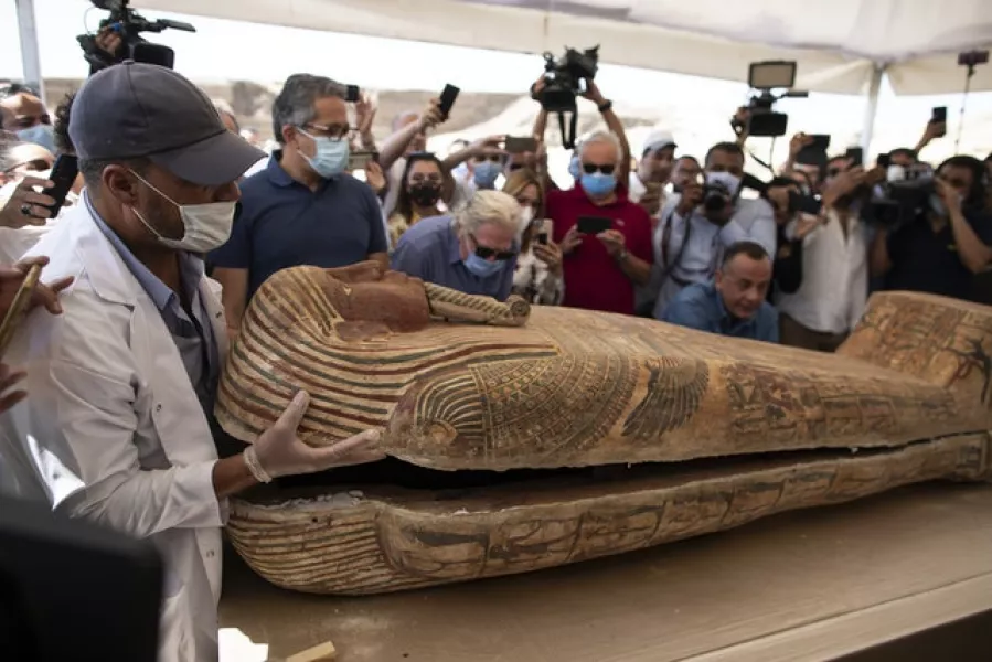 A member of an archaeological team opens a sarcophagus at the Saqqara archaeological site south of Cairo (Mahmoud Khaled/AP)