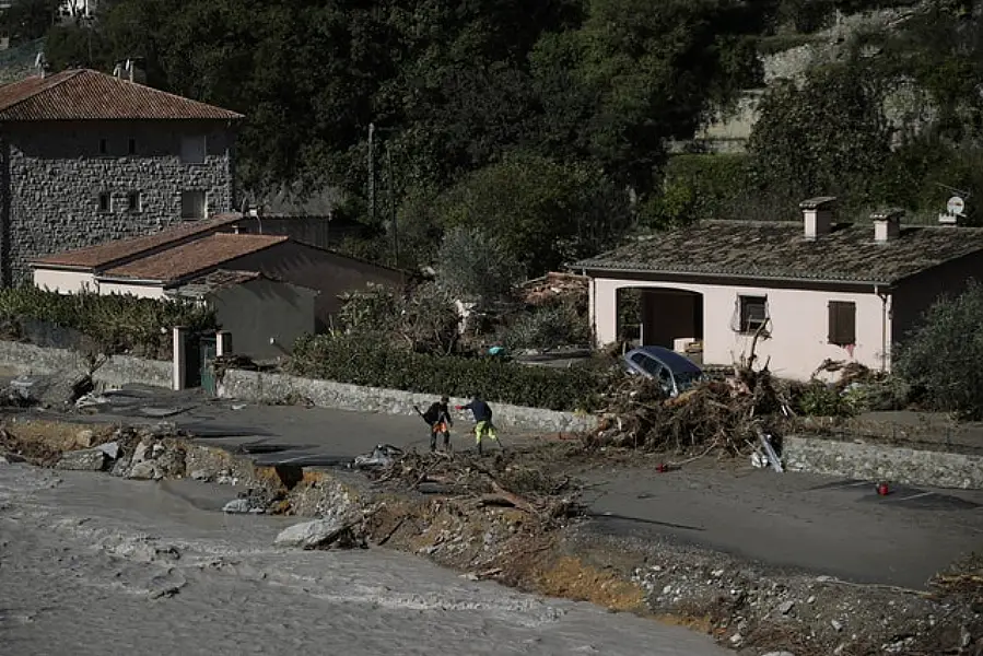 Residents try to remove a tree that fell on the road in Breil-sur-Roya, near the border with Italy (Daniel Cole/AP)