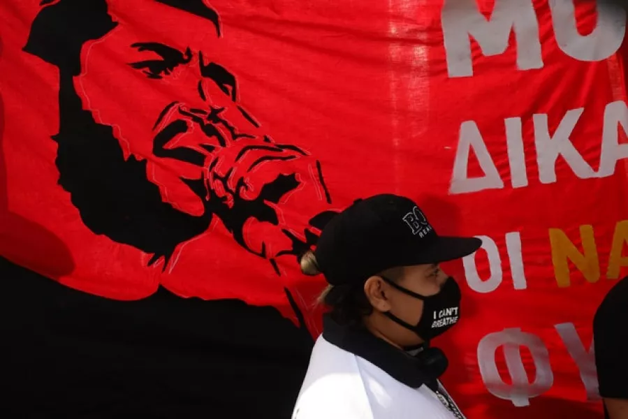 A woman stands in front of a banner depicting Greek rap singer Pavlos Fyssas (Yorgos Karahalis/AP)