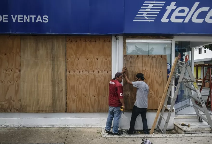 Men board up a store as Hurricane Delta approaches (Victor Ruiz Garcia/AP)